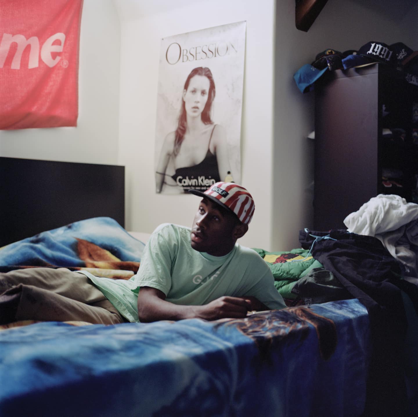 Tyler the creator sleeping in a dark room with a funny smirk